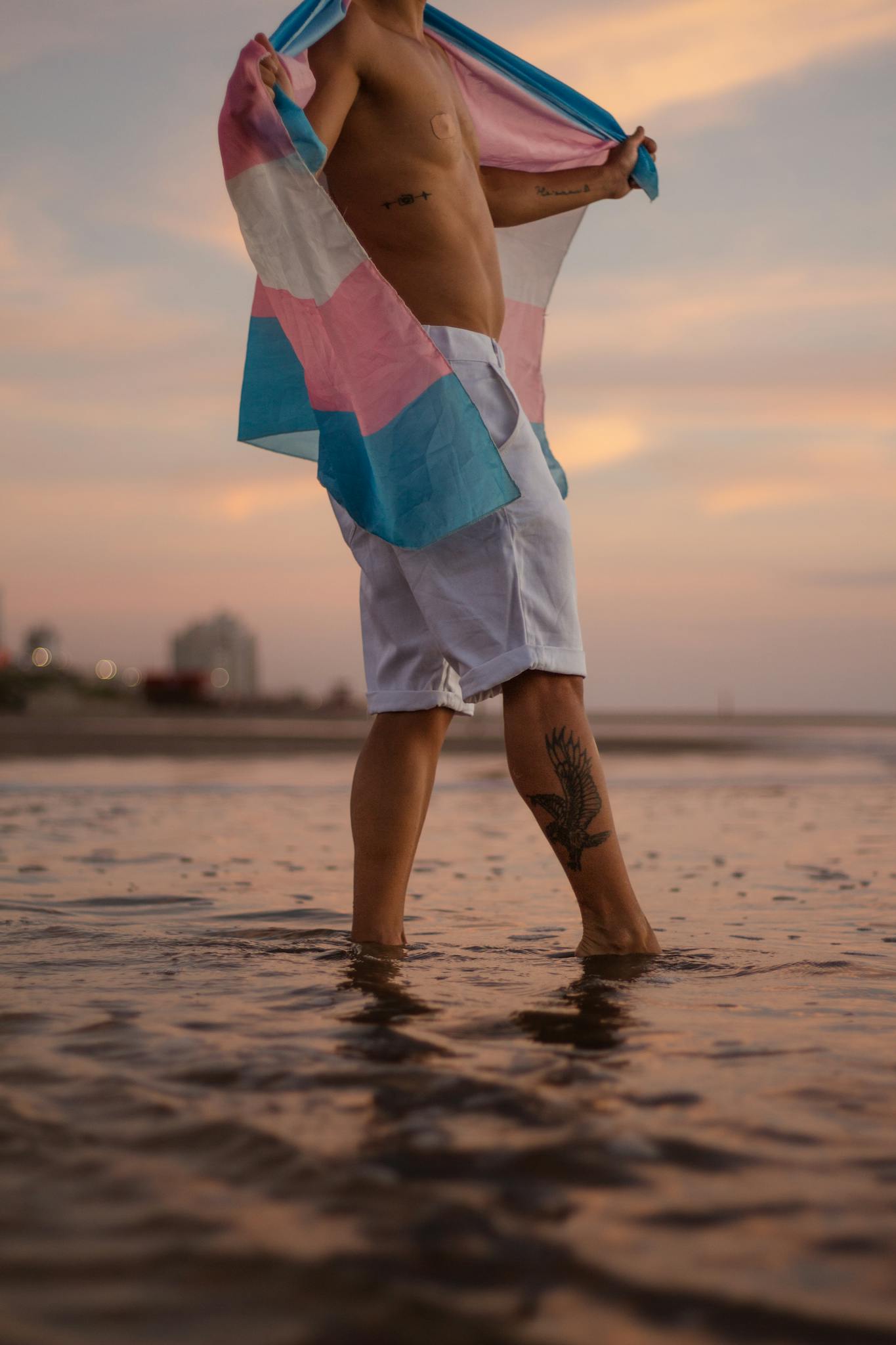 A man standing in the water with a pink and blue towel