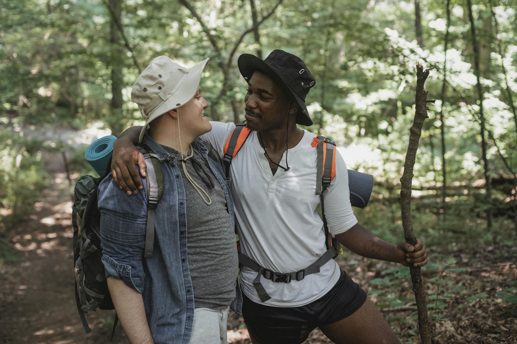 Happy young boyfriends hugging together during hiking trip